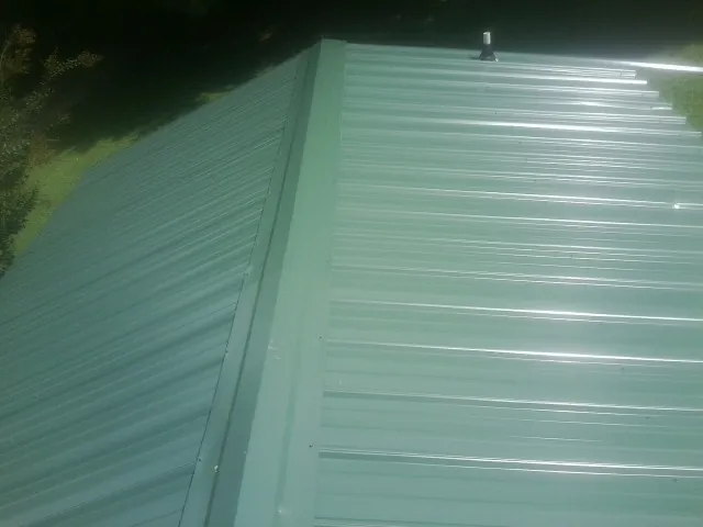 New green metal panels meeting at the ridge of a roof — Flat Roof Repair work by our crew in Douglas