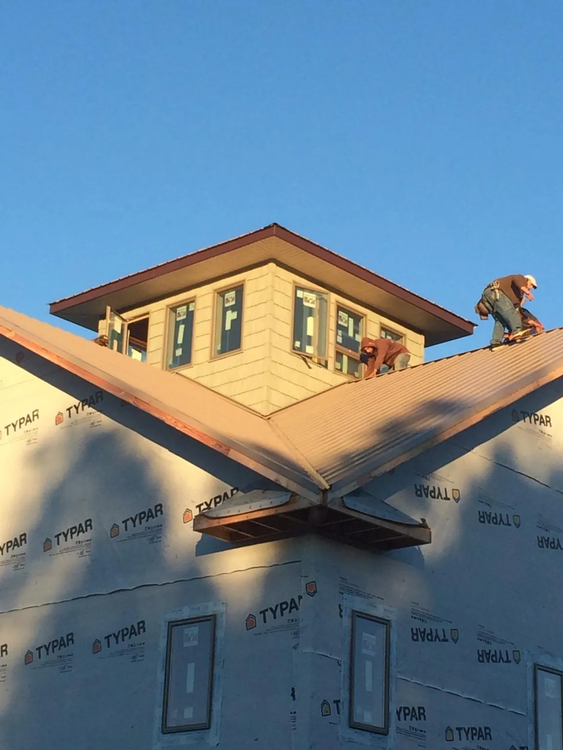 Roofers working around a rooftop cupola on a new metal roof at sunset — Roof Waterproofing in Douglas by Roofing Brothers